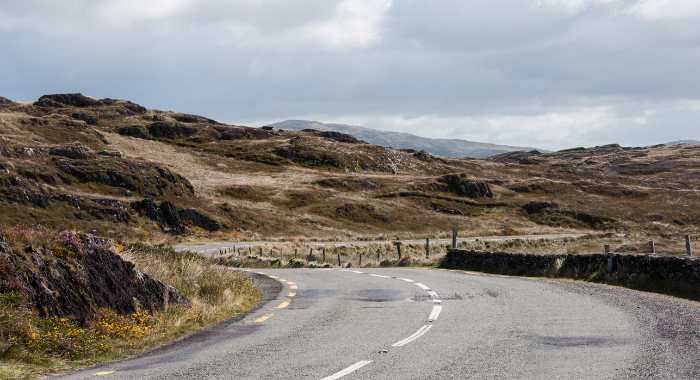 Atlantic Way 1 The Wild Atlantic Way in Ireland. A road bends to the left with hills in the background.