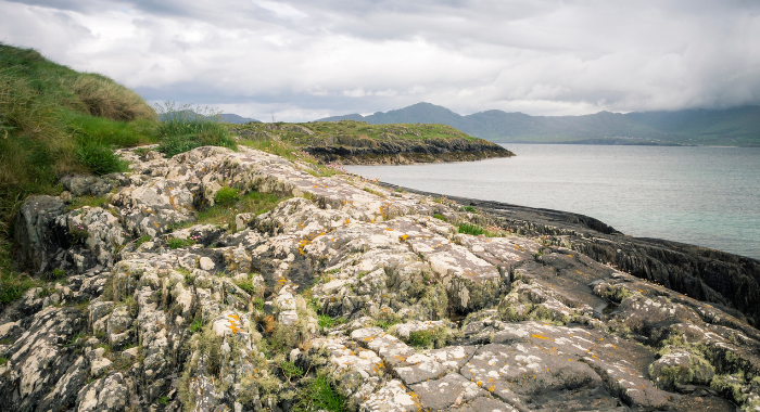 Beara White stone sits in the forefront of the image with hills in the background and water to the right.