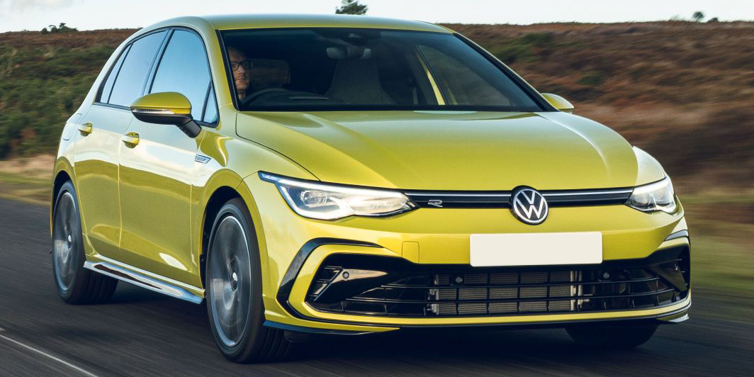 A man driving a Volkswagen Golf GTI on a road at speed.