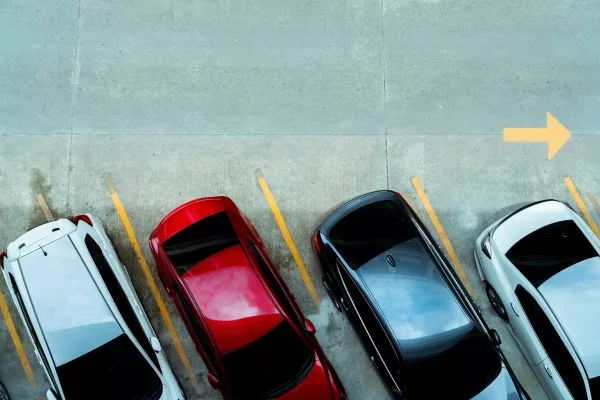 An areal view of 4 cars parked in a row in a car park.