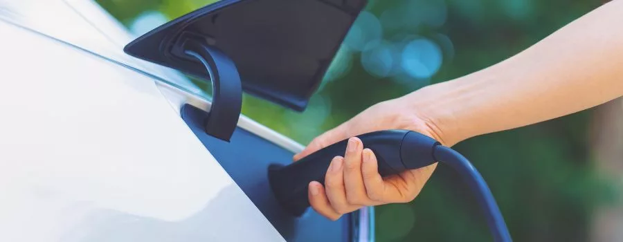 Electric Vehicles A person plugging a charger into an electric car.
