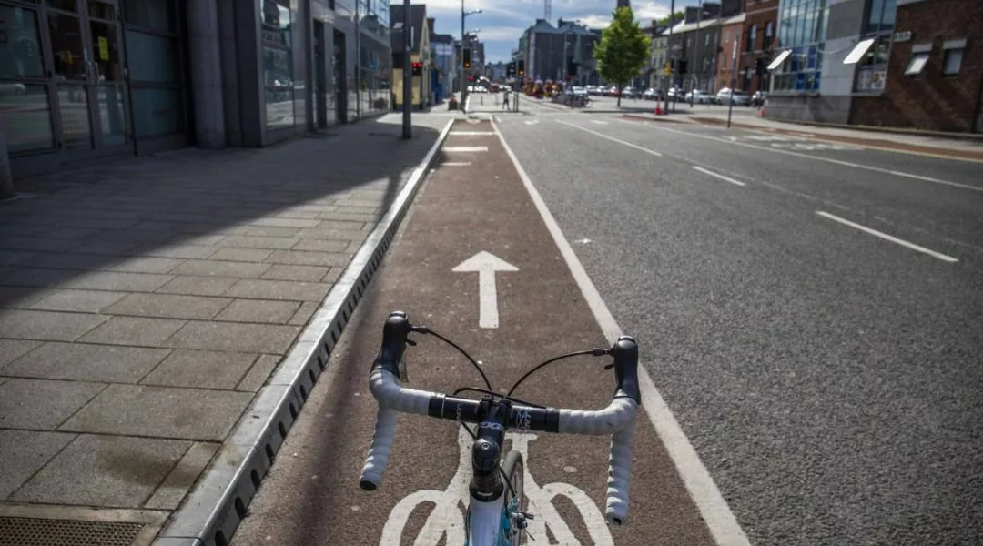 A photo taken from the seat of a bike looking forward, as it sits in a cycle lane.