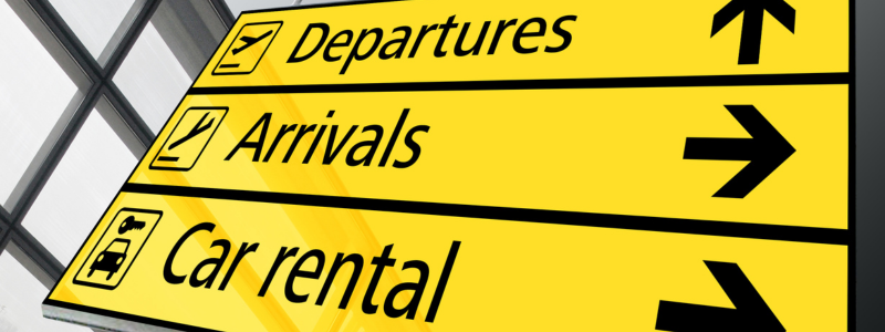 <br />
An airport information sign indicating directions for departures, arrivals, and car rental, with yellow background and black text.
