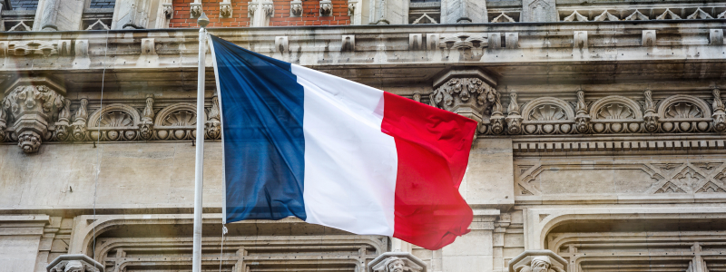 A French flag waving in front of a building.