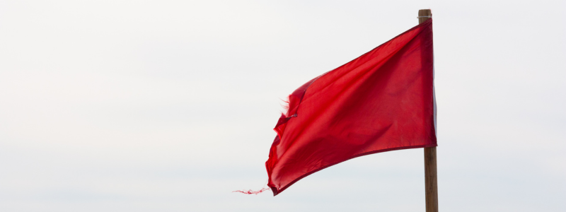 Red Flag A slightly tired red flag waving in the wind, on an overcast day.