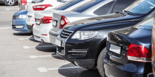 A row of cars parked up in daylight.