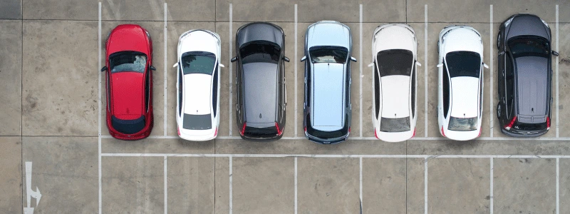 An overhead shot of a row of cars parked in spaces, all facing in the same direction.