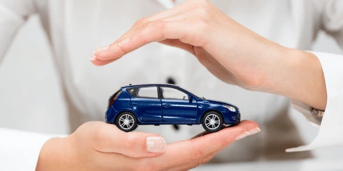Two hands protecting a toy car, representing car care and insurance.