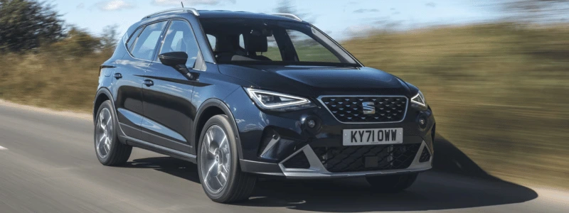 A black Seat Arona driving on a country road at speed.