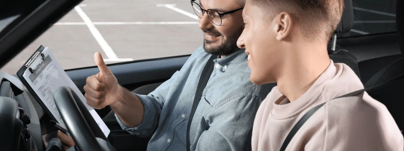 A person in a driving test, with the instructor signalling a thumbs up, suggesting they have passed.