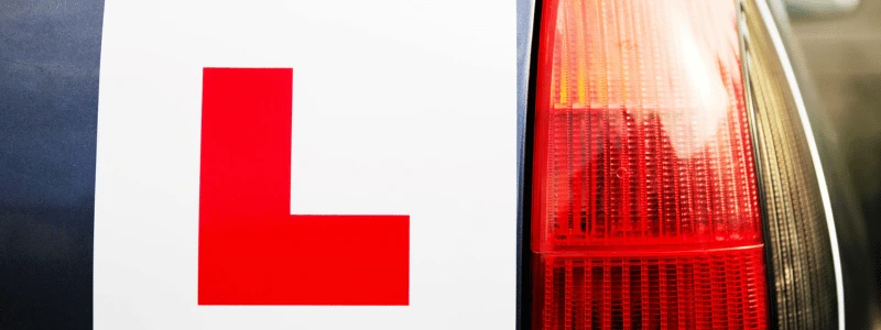 A view of a car from behind, with a learner sticker in full view. 