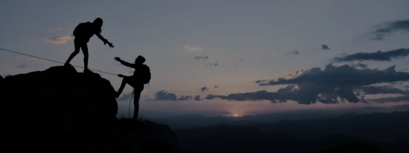 A person helping another person up onto a rock, symbolising teamwork and partnership.