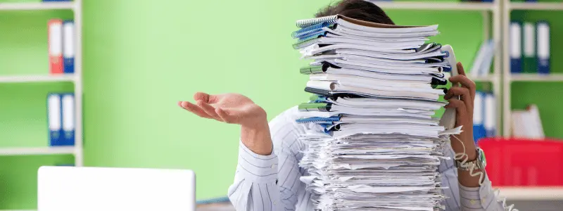 A person blocked by an overwhelming stack of papers.