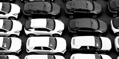 An overhead view of rows of cars in black and white.