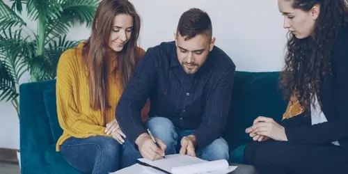 A salesperson watching a couple signing a contract.