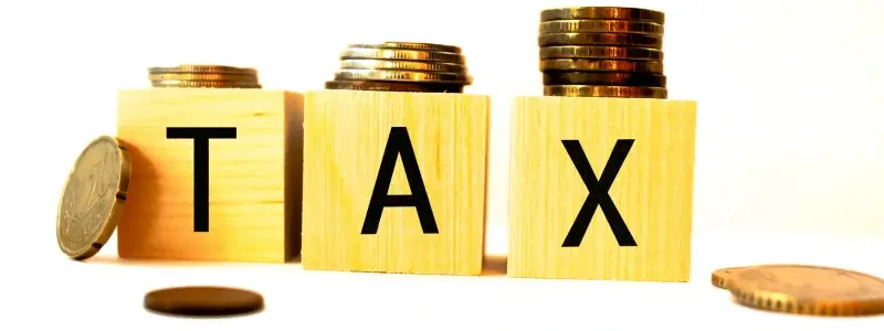 Letter blocks spelling out 'TAX' with coins surrounding it.
