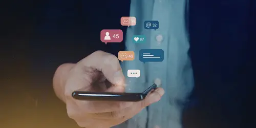 A person using their phone and social media notifications floating out of the phone.