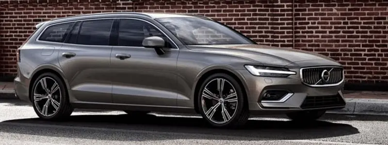 A grey Volvo V60 parked in front of a wall.