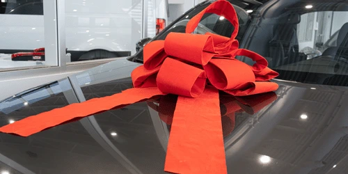 A gift bow on a car bonnet.