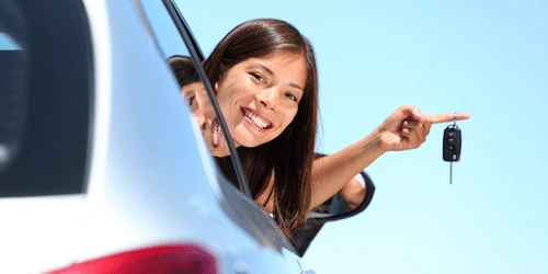 A young driver smiling looking out of a car window.