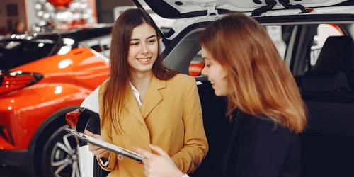 A salesperson talking to a customer in a car showroom.