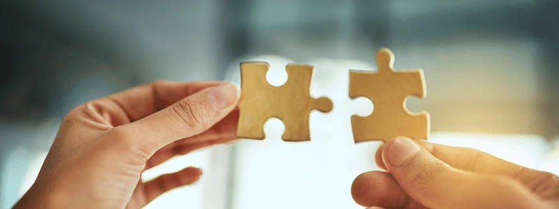 Two hands putting jigsaw pieces together.