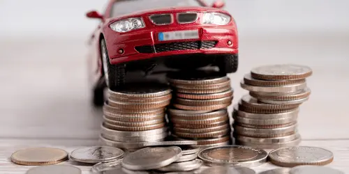 A toy car on top of stacks of coins.